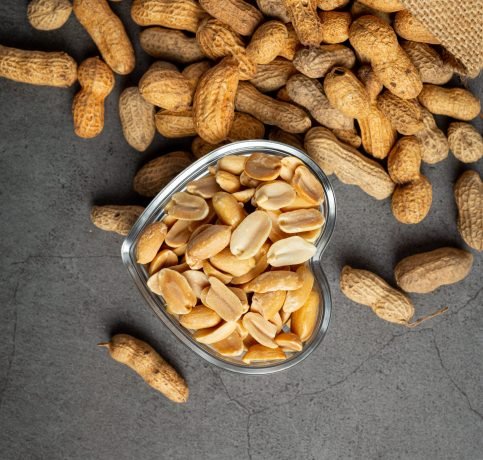 Groundnuts in heart shape plate put next to  a sack of groundnuts